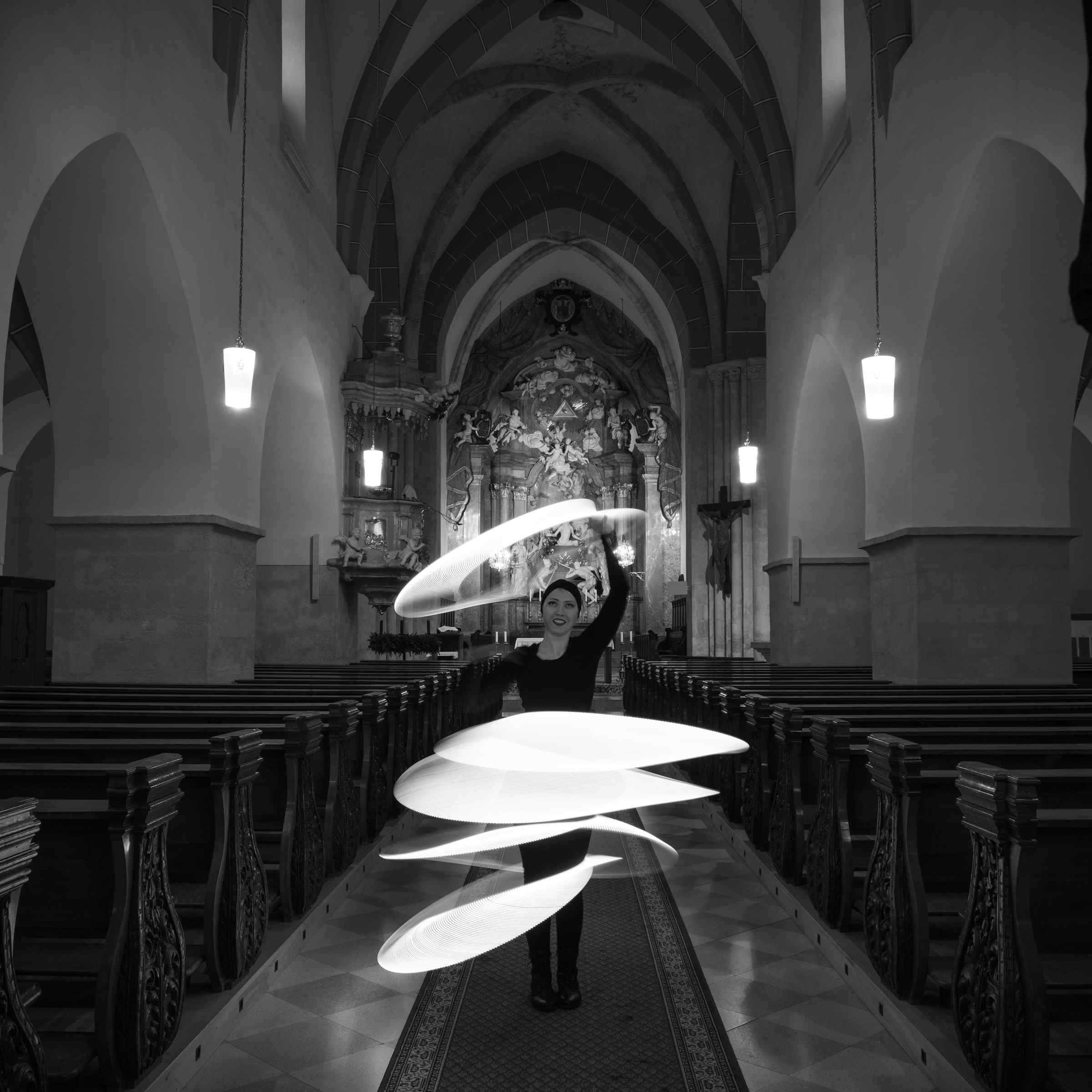 Schwarzweißaufnahme des Mittelgangs im Kirchenschiff.